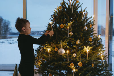 Boy decorating christmas tree at home