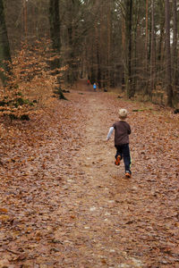 Rear view of woman walking in forest during autumn