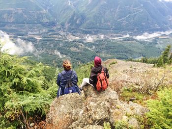 Rear view of couple sitting on rocky mountain