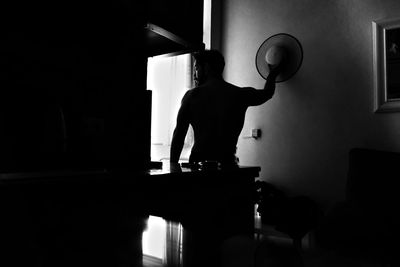 Rear view of silhouette man standing by table at home
