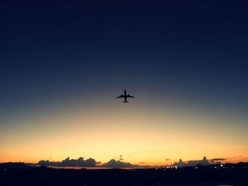 Low angle view of silhouette airplane against clear sky during sunset