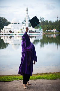 Rear view of woman standing on shore against sky