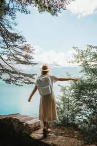 Rear view of woman looking at lake against sky