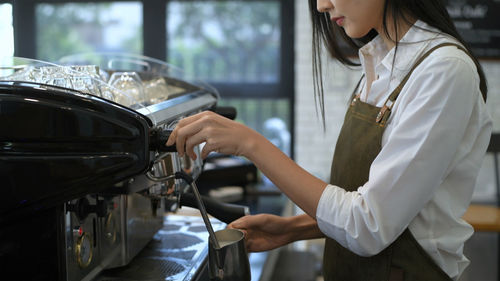 Midsection of barista preparing coffee at cafe