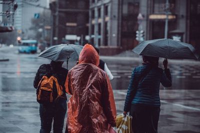 Rear view of people walking on wet street during rainy season