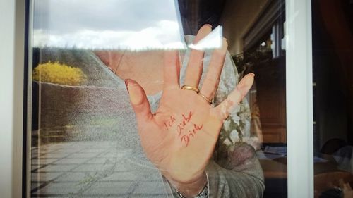 Close-up of man hand against window