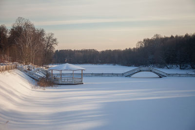 Snow covered field against sky during sunset