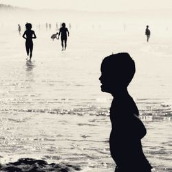 Silhouette people on beach against sky