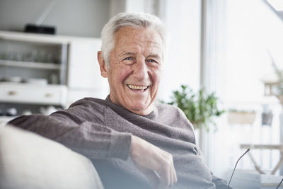 Portrait of happy senior man sitting on couch at home