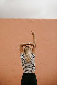 Rear view of woman standing against wall