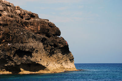 Rock formations by sea against sky