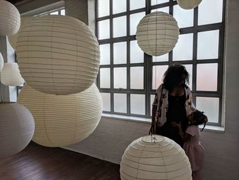 Mother and daughter standing by paper lanterns hanging against window