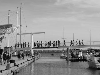 People on pier by sea against sky