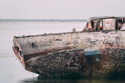 Abandoned boat on sea against sky