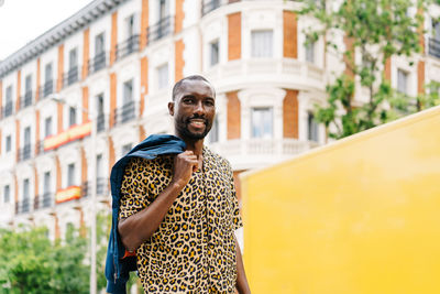 Portrait of young man standing against building