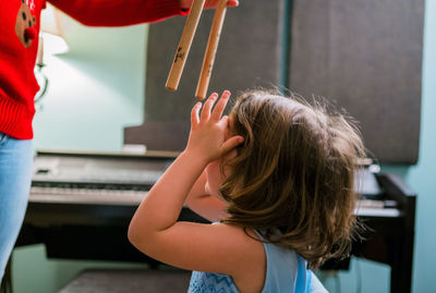 Rear view of girl playing piano