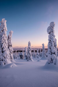 Snow covered landscape against sky during sunset