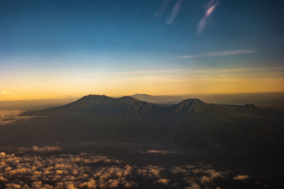 Aerial view of snowcapped mountains against sky during sunset