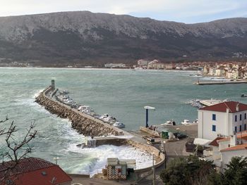 High angle view of buildings by sea against mountains