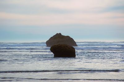 Rocks on sea shore against sky