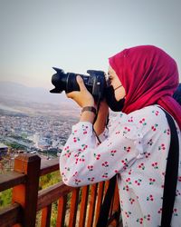 Midsection of woman photographing against sky