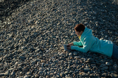 Side view of boy sitting on rock