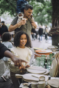 Curious girl looking at products while standing near stall at flea market