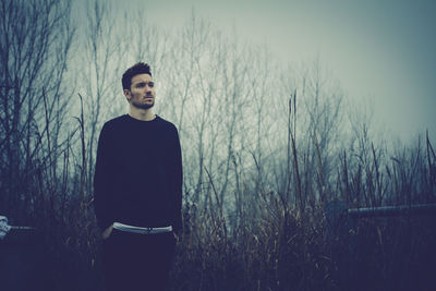 Front view of young man standing on field during foggy weather