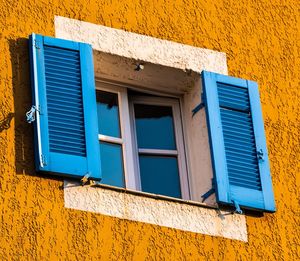 Low angle view of blue windows on wall of building