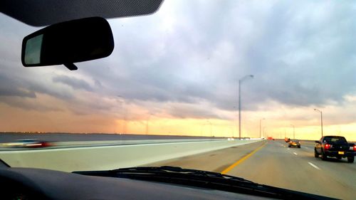 Cars on road against sky during sunset