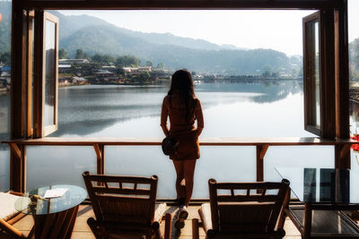 Rear view of woman standing at restaurant by lake