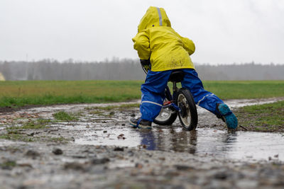 Rear view of a man riding motorcycle on rainy day