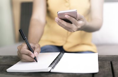 Midsection of woman using mobile phone on table