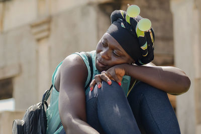 African woman with headdress and round sunglasses from ghana sitting and enjoying in takoradi ghana