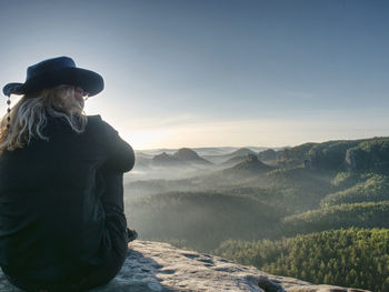 Man standing on mountain against sky during sunset