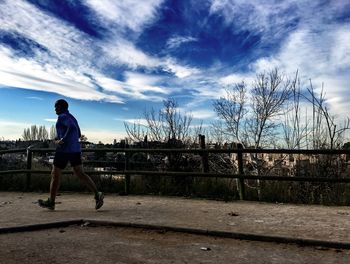 Silhouette of girl standing against cloudy sky