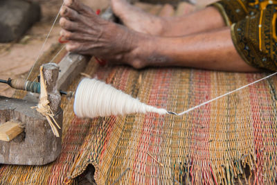 Low section of person weaving loom on mat