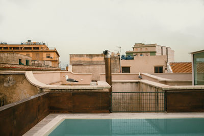 Buildings by swimming pool against sky