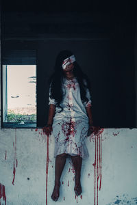 Portrait of young woman standing against wall during halloween