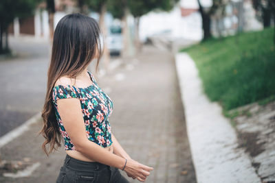 Rear view of woman standing on footpath