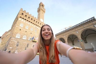 Self portrait of beautiful woman smiling at camera in piazza della signoria square in florence,italy