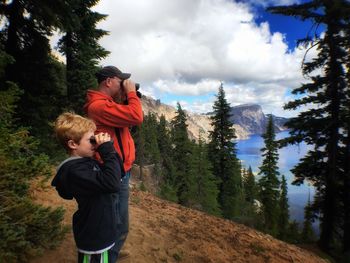 Father and son looking through binoculars at crater lake