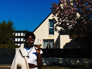 Portrait of woman standing against house