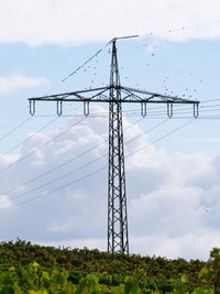 Low angle view of electricity pylon on field against sky