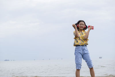 Full length of smiling woman at beach against sky