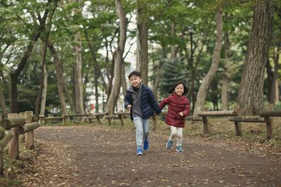 Cute siblings running against trees at park