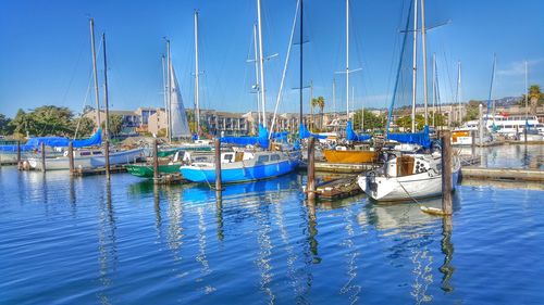 Boats moored at harbor against blue sky