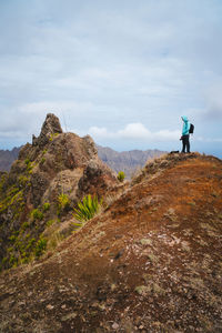 Man standing on rock against sky