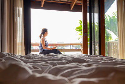 Woman sitting on bed at home