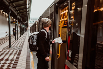 Side view of man with backpack entering in train